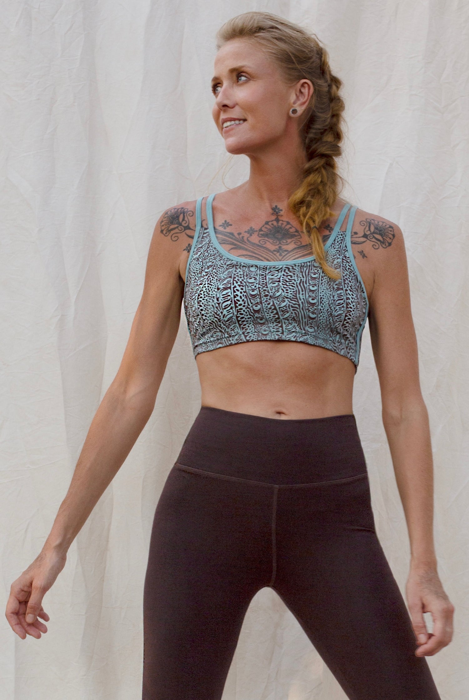 Woman wearing an Argus patterned sports bra and brown leggings against a plain background