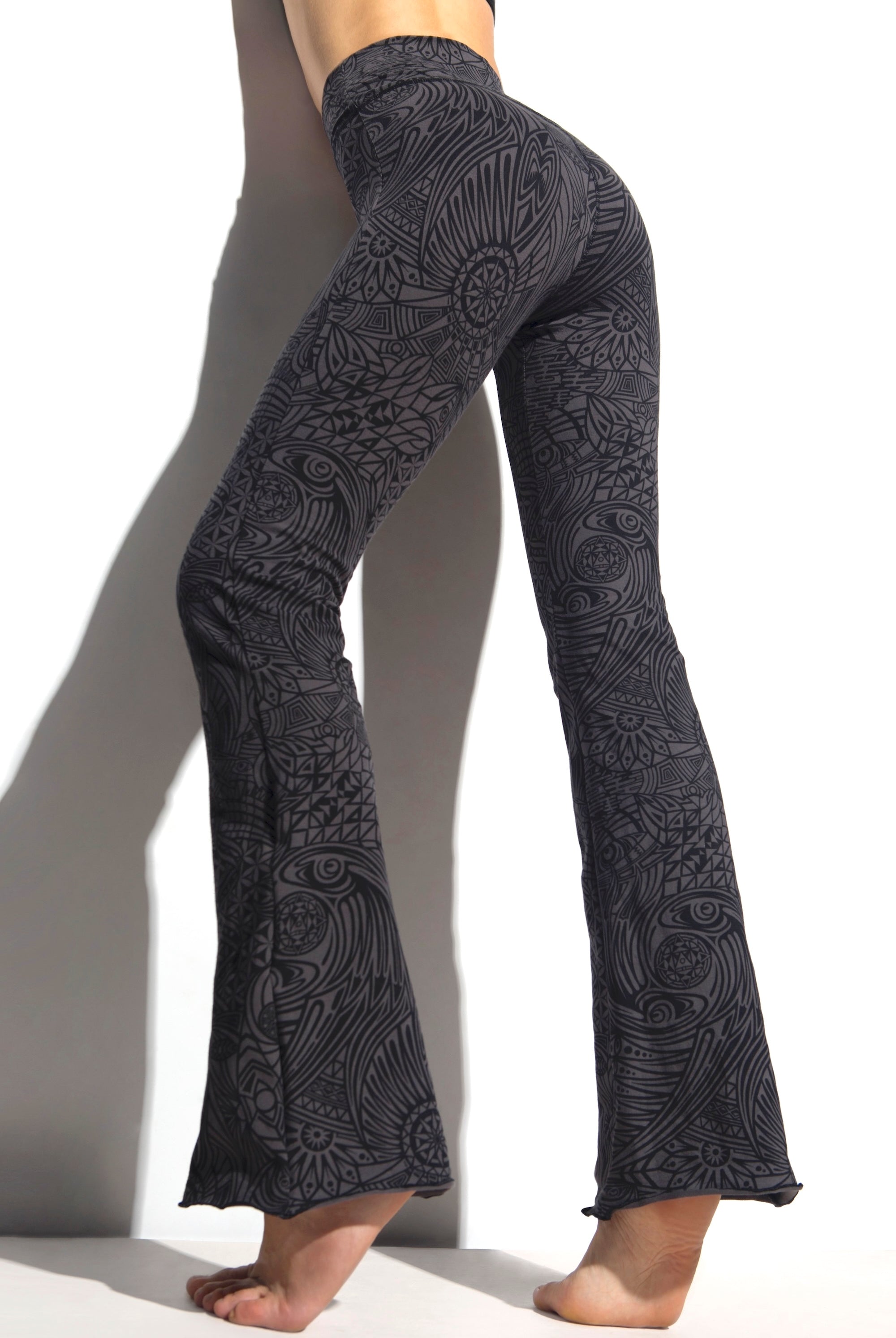 A woman wearing Funky Simplicity tribal-print flared leggings in grey black color shown from the BACK
