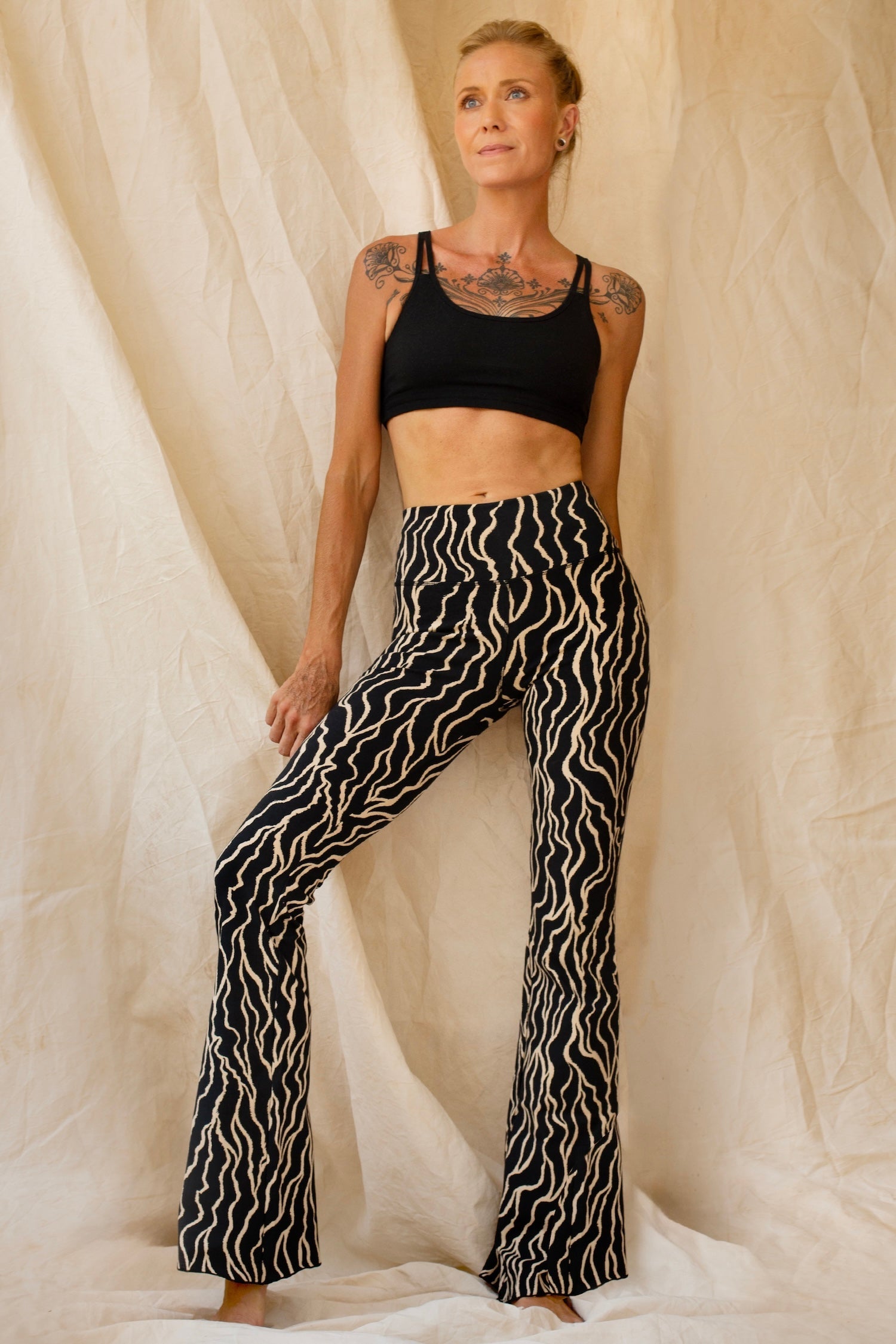 woman wearing a pair of flared Leggings with a black Lionfish print together with a black cross back sportsbra
