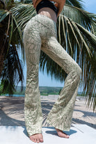 Model wearing Funky Simplicity Flares in Cream Olive Feather print made from cotton lycra - with green palm trees and a river on the background - shown from the front