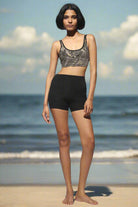 High Waist Shorts black from the front with cream black tribal cross-back bra worn on the beach with the sea on the background