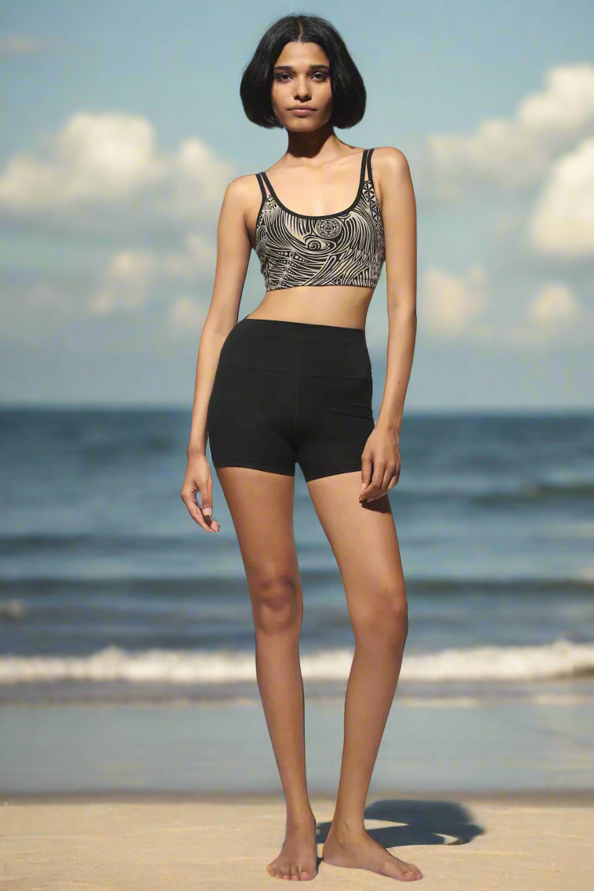 High Waist Shorts black from the front with cream black tribal cross-back bra worn on the beach with the sea on the background